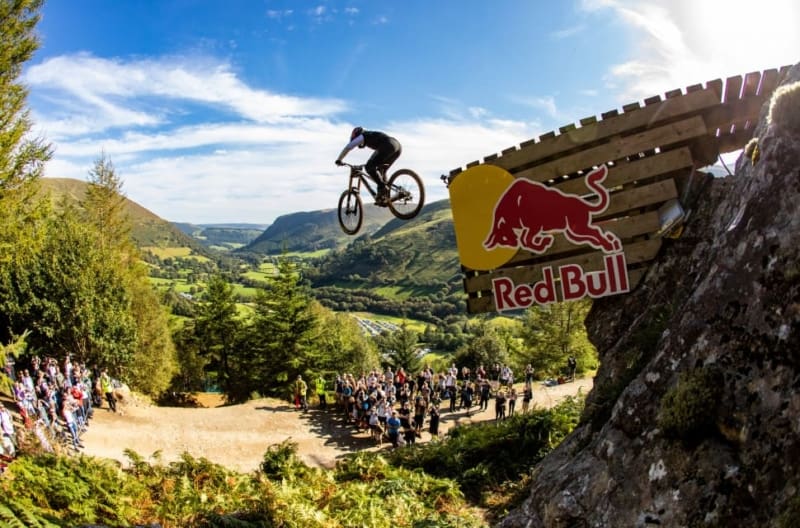 A picture of a biker coming off a ramp in a Red Bull event